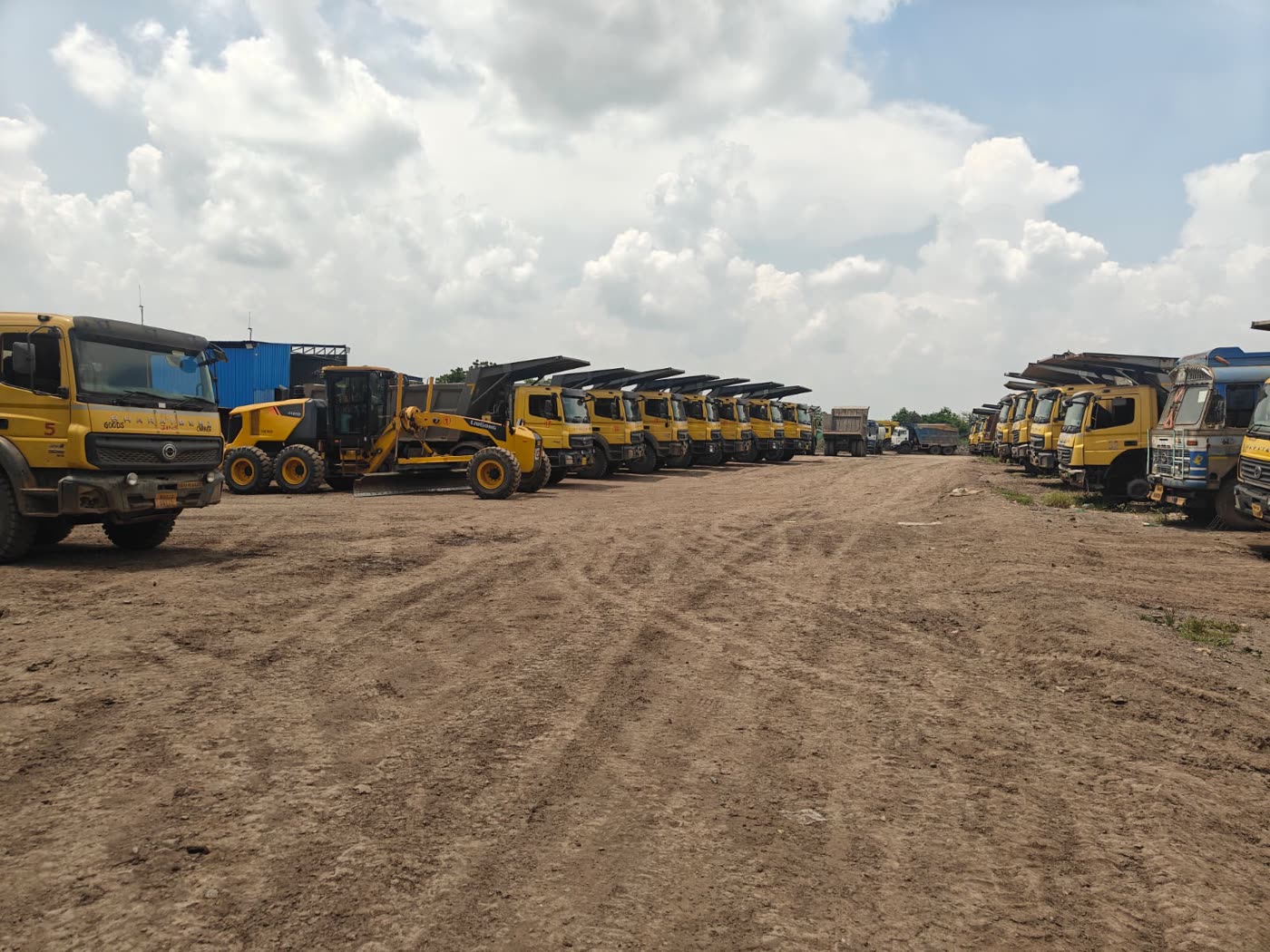 Fleet of tippers and earthmoving machinery lined up on a mine haul road